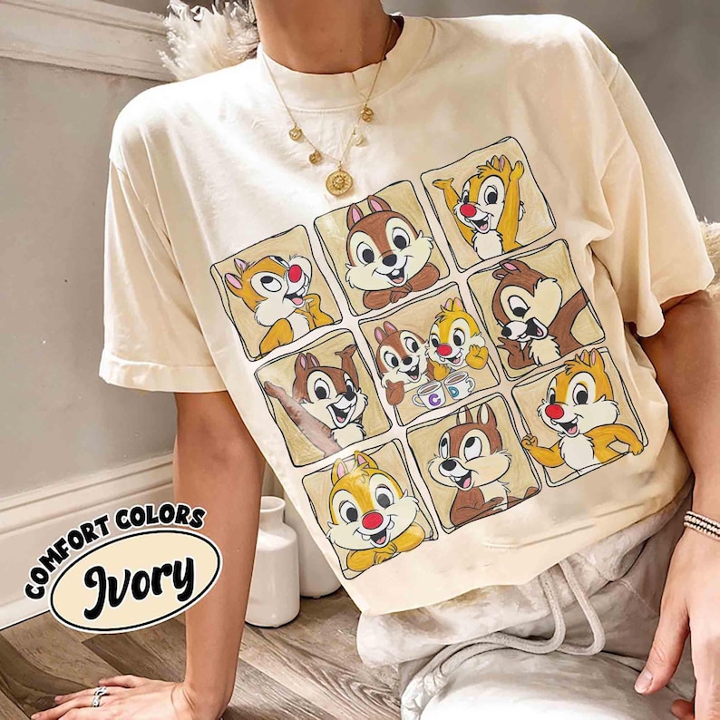 May include: Ivory-colored t-shirt featuring a grid of cartoon chipmunks. The shirt has short sleeves and a crew neck. The text "COMFORT COLORS Ivory" is printed on the lower left side of the shirt.