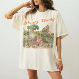 May include: Cream-colored t-shirt with a Disney World graphic. The graphic features a castle, tree, and the words "Disney World" and "The most magical place on earth."