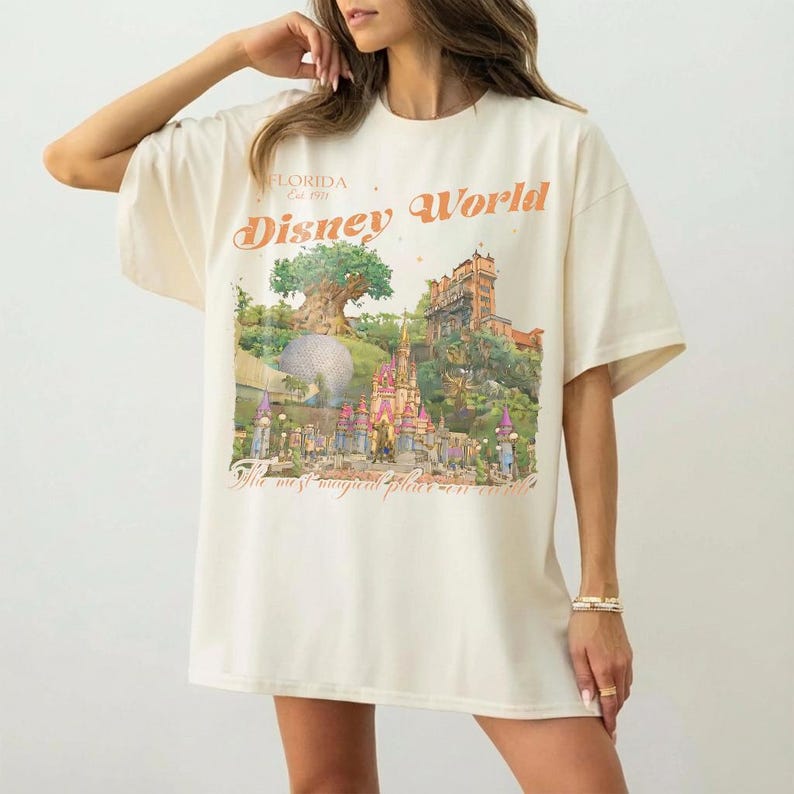 May include: Cream-colored t-shirt with a Disney World graphic. The graphic features a castle, tree, and the words "Disney World" and "The most magical place on earth."