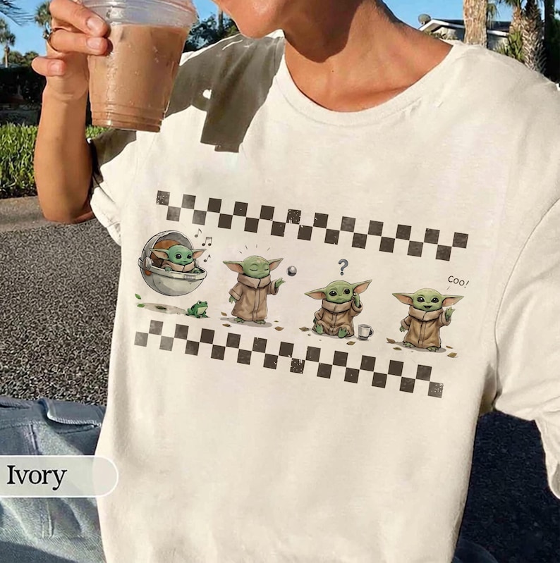 May include: Ivory-colored t-shirt featuring a graphic of a character from a popular science fiction series. The design includes the character in various poses, with a checkered border. The word "Cool" is also printed on the shirt.
