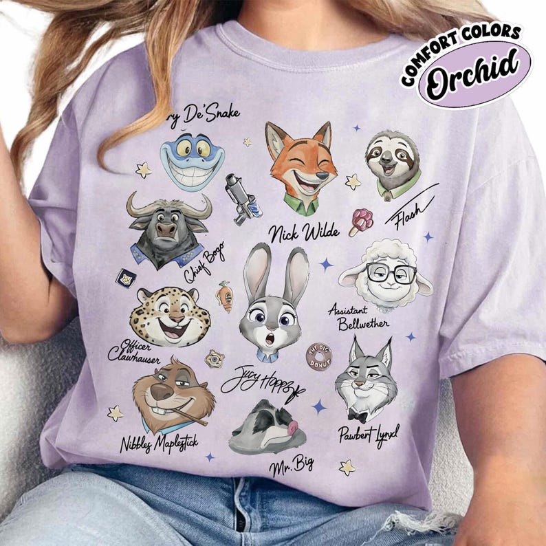 May include: A light purple t-shirt featuring cartoon characters from Zootopia. The shirt includes the text "COMFORT COLORS Orchid" and character names like Nick Wilde, Judy Hopps, and Flash. The design is a colorful illustration.