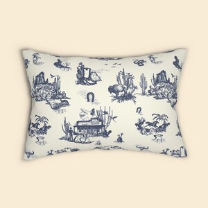 Front view of a cream lumbar pillow with navy blue Western toile print, shown on a plain beige background