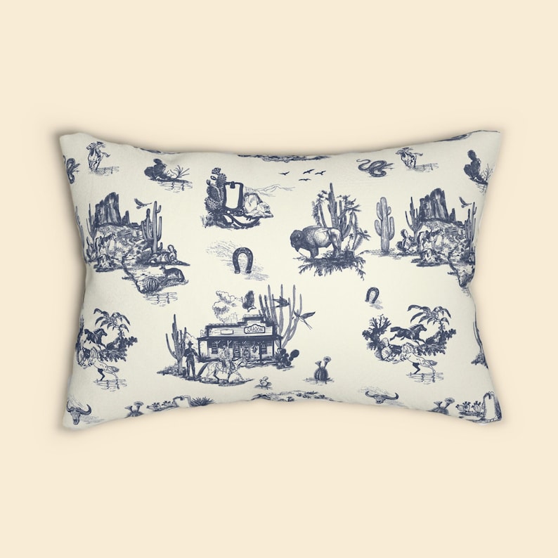 Front view of a cream lumbar pillow with navy blue Western toile print, shown on a plain beige background