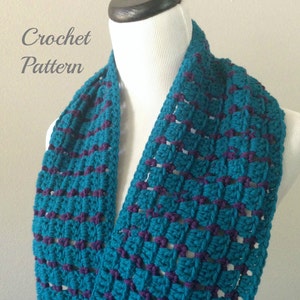 May include: A teal and purple crocheted infinity scarf. The scarf is made with a simple stitch pattern and has a textured look.