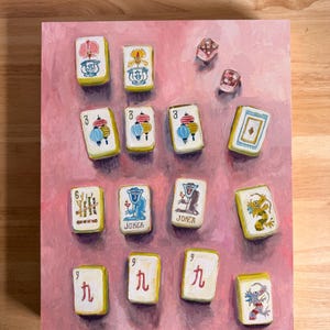 May include: A painting of Mahjong tiles and dice on a pink background. The tiles are white with colorful illustrations and Chinese characters. The dice are translucent with red dots. The artwork is a still life.