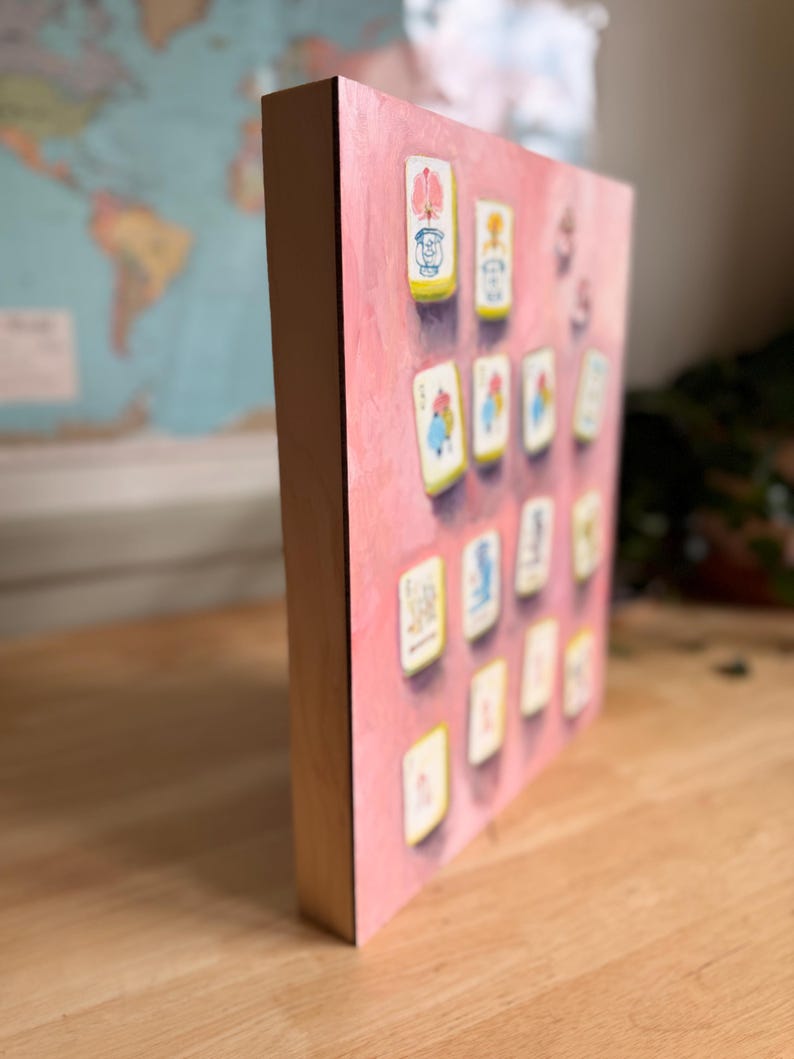 May include: A pink canvas print featuring a collection of illustrated cards. The cards have a white border and are arranged on a pink background. The wooden frame adds a natural contrast to the artwork.