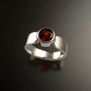 Puede incluir: Un anillo de plata con una piedra preciosa roja engastada en un engaste de bisel.