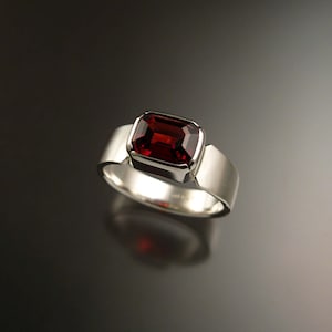 May include: A silver ring with a large, rectangular, red gemstone set in a bezel setting.