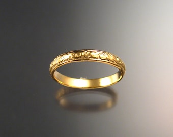 May include: A simple gold wedding band with a delicate floral design engraved around the band.