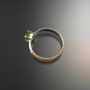 May include: A silver ring with a textured band and a green gemstone.