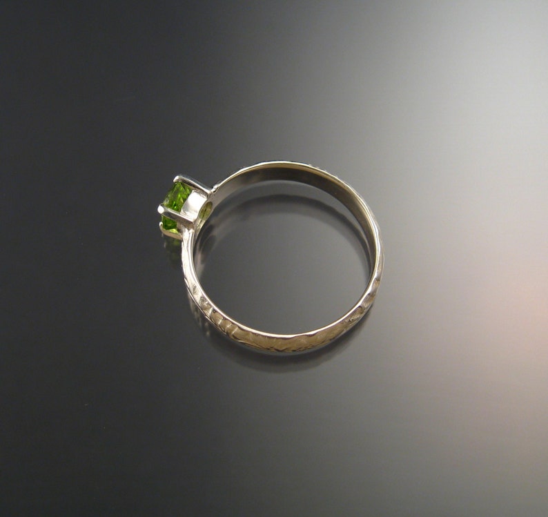 May include: A silver ring with a textured band and a green gemstone.