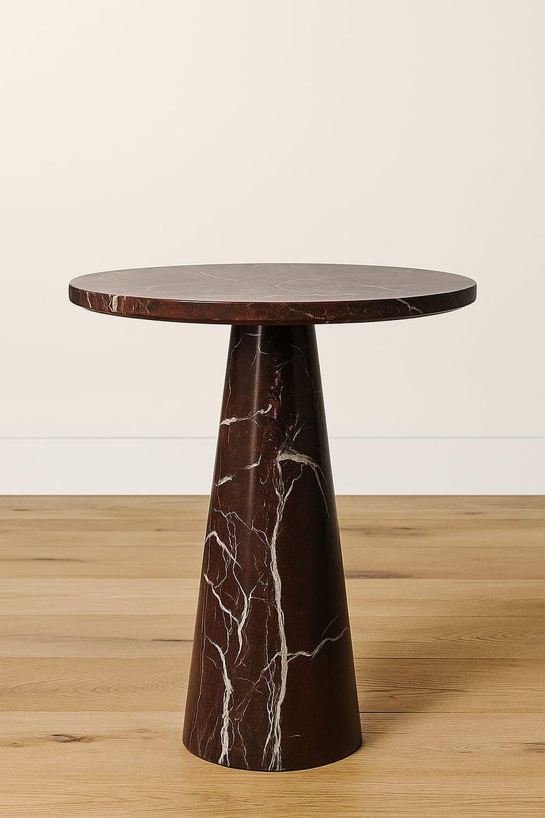 May include: A dark brown marble side table with a round top and a conical base. The table has white veining throughout, adding a natural pattern. The table is a stylish accent piece.