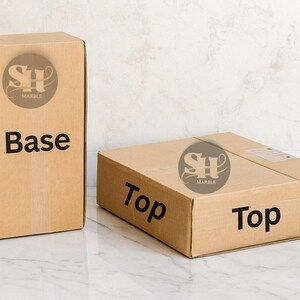 Puede incluir: Dos cajas de cart&oacute;n marr&oacute;n con las etiquetas "Base" y "Top". Las cajas tienen el logotipo "SH Marble". Una caja est&aacute; de pie, la otra est&aacute; tumbada. Las cajas est&aacute;n sobre una superficie de m&aacute;rmol.