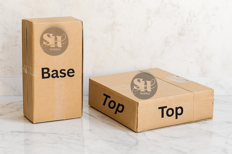Puede incluir: Dos cajas de cart&oacute;n marr&oacute;n con las etiquetas "Base" y "Top". Las cajas tienen el logotipo "SH Marble". Una caja est&aacute; de pie, la otra est&aacute; tumbada. Las cajas est&aacute;n sobre una superficie de m&aacute;rmol.