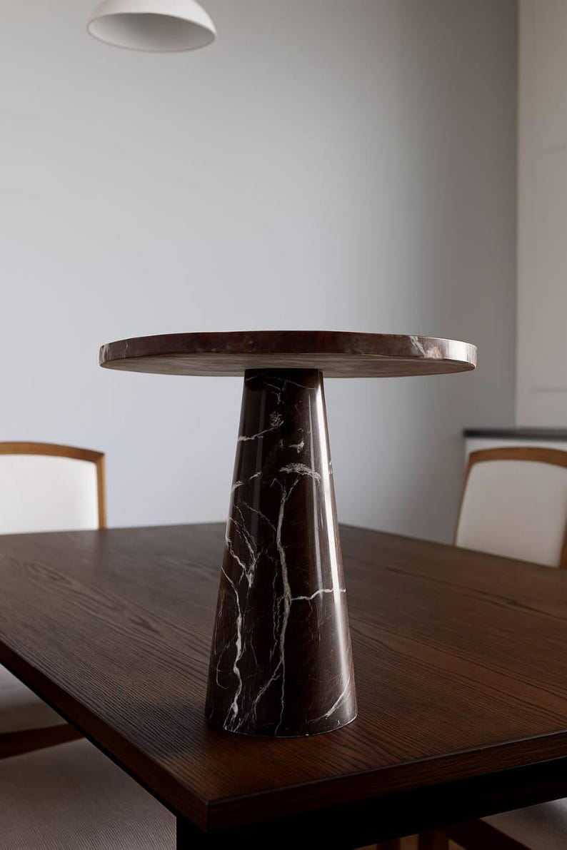 May include: A brown marble side table with a round top and a conical base. The table has white veining throughout the dark brown marble. The table is approximately 20 inches in diameter and 24 inches tall.