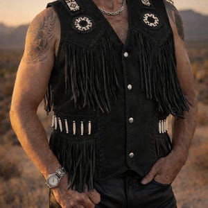 May include: Black suede vest with fringe, decorative stitching, and silver-tone buttons. The vest features white and cream-colored embellishments on the shoulders and pockets. A classic western-inspired garment.