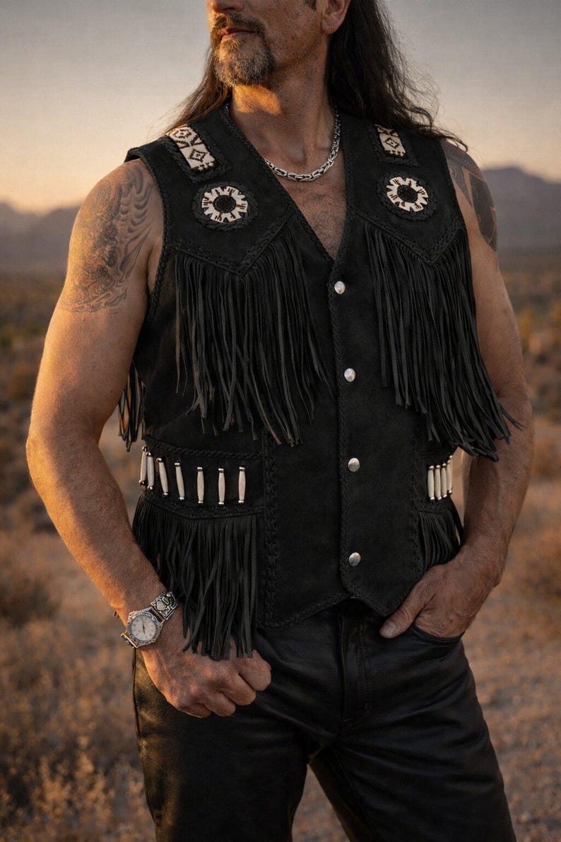 May include: Black suede vest with fringe, decorative stitching, and silver-tone buttons. The vest features white and cream-colored embellishments on the shoulders and pockets. A classic western-inspired garment.