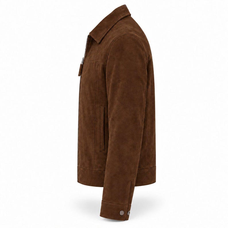 Peut inclure: Une veste en daim marron vue de profil. La veste pr&eacute;sente un col classique, une fermeture &eacute;clair int&eacute;grale sur le devant avec une tirette marron assortie, des manches longues avec des poignets boutonn&eacute;s et des poches fendues verticales.