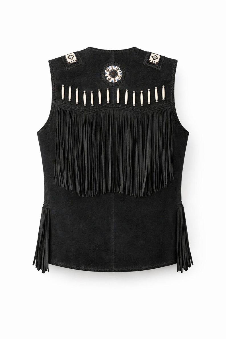 May include: Black suede vest with fringe and decorative beading. The vest features long fringe along the bottom and a row of fringe across the chest. The shoulders and back are adorned with white and silver beads. A circular beaded design is centered on the back.