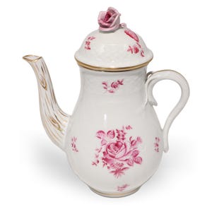 May include: White porcelain coffee pot with a lid and a rose-shaped finial. The pot features pink rose floral designs and gold trim. The spout has a textured, gold-painted design. The handle is curved and white.