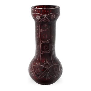 Può includere: Un vaso di vetro rosso rubino con intricati motivi intagliati. Il vaso presenta una base bulbosa, un collo lungo e cilindrico e un bordo svasato. I disegni intagliati includono scoppi di stelle, forme geometriche e dettagli a puntini.