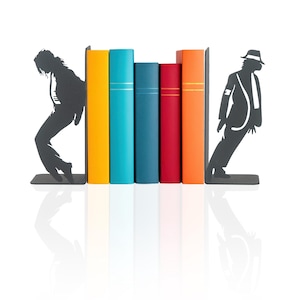 May include: Black metal bookends shaped like silhouettes of a person in a dance pose. The bookends are holding up a row of colorful books, including yellow, blue, red, and orange.