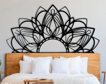 Puede incluir: Una gran pieza de arte mural de mandala de metal negro está montada sobre una cama. El intrincado diseño presenta una forma de semicírculo con patrones florales y geométricos. La cama tiene un cabecero de madera y ropa de cama blanca.