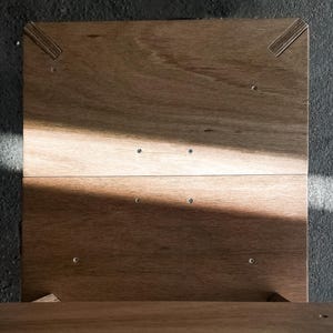 May include: A wooden box with a hinged lid. The box is made of light brown wood and has a simple design. The lid is open and the inside of the box is visible.
