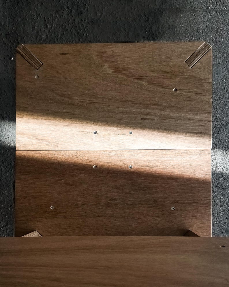 May include: A wooden box with a hinged lid. The box is made of light brown wood and has a simple design. The lid is open and the inside of the box is visible.