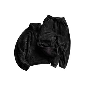 Puede incluir: Un conjunto de chándal de forro polar negro. El conjunto incluye una chaqueta con cremallera, cuello alto y bolsillo de canguro, y un pantalón de chándal a juego con cordón. La tela tiene un aspecto suave y texturizado.