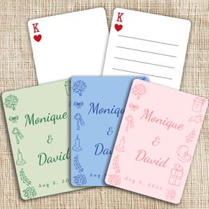 May include: A collection of personalized wedding invitation cards. The cards feature the names "Monique & David" and the date "Aug 8, 2026". The cards are in pastel colors with decorative elements and a playing card design.