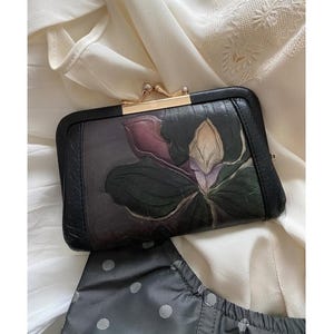 Cartera pequeña de mujer estilo retro de piel negra con orquídeas.