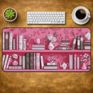 May include: A rectangular desk mat featuring a pink-toned illustration of two shelves filled with various books, floral arrangements in vases, and teapots. The design includes a repeating floral wallpaper pattern in the background.
