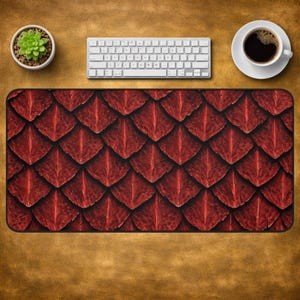 May include: A rectangular desk mat featuring a repeating pattern of deep red, textured dragon scales. The surface displays a detailed, layered design with dark shadows and highlights that create a realistic, three-dimensional appearance across the mat.