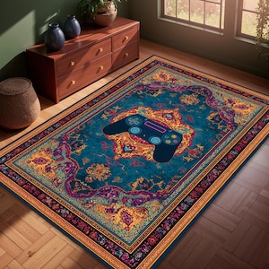 May include: A rectangular area rug with a teal background and a central design of a black video game controller. The rug features a traditional floral pattern in shades of gold, purple, and orange, with a decorative border.