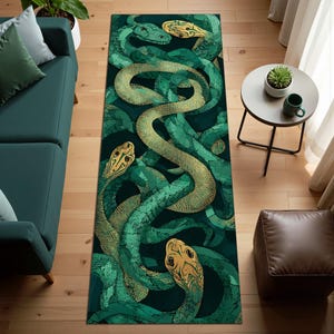 May include: A rectangular rug with a detailed illustration of intertwined snakes in shades of green and gold against a dark background. The rug's design showcases the snakes' intricate patterns and textures. The rug is placed on a wooden floor.