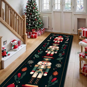 May include: A long, rectangular black Christmas runner rug featuring three nutcracker figures in green, red, and white. The rug is decorated with holly, ornaments, and snowflakes. A Christmas tree and wrapped gifts are in the background.