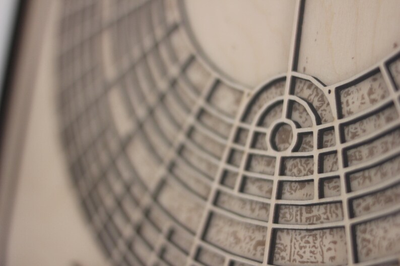 May include: Close-up of a detailed, geometric design with a circular pattern. The design features a series of interconnected lines and shapes, creating a complex, architectural aesthetic. The colour palette is neutral, with shades of grey and beige.