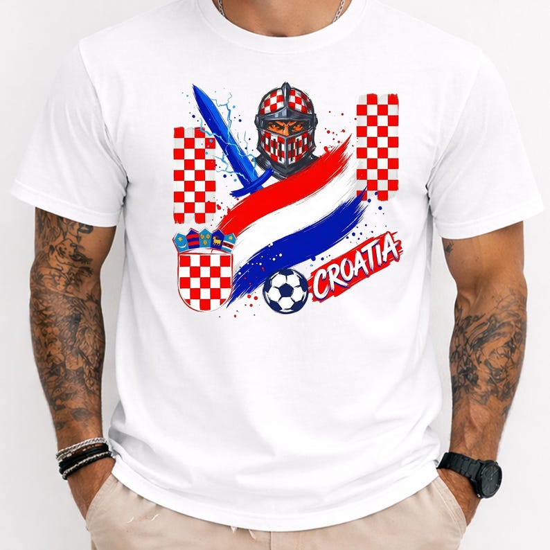 May include: A white t-shirt featuring a graphic print of a knight in a red and white checkered helmet, a blue sword, a soccer ball, the Croatian coat of arms, red, white, and blue brush strokes, and the text CROATIA in a red stylized font.