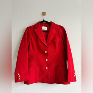 May include: A red blazer with gold buttons. The blazer has a classic style and is made of a soft, textured fabric.