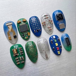 May include: A set of ten almond-shaped nail art pieces featuring electronic components. Designs include integrated circuits, resistors, copper coils, LED lights, and printed circuit board patterns in blue, green, and clear resin finishes.