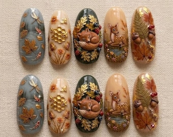 May include: A set of ten oval-shaped press-on nails featuring intricate 3D autumn-themed designs. The motifs include a sleeping fox, a deer, golden honeycombs, koi fish, dragonflies, maple leaves, ferns, acorns, and berries in warm earth tones.