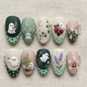 May include: A set of ten press-on nails featuring 3D ghost designs, botanical elements, berries, lavender, and a campfire. The nails are decorated with various shades of green, cream, and soft pink, incorporating polka dot patterns and stars.