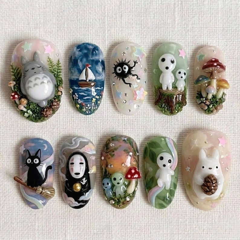 Puede incluir: Un conjunto de diez dise&ntilde;os de u&ntilde;as ovalados pintados a mano. Cada u&ntilde;a presenta un personaje o escena en miniatura en 3D diferente, incluyendo un velero, un gato negro en una escoba y esp&iacute;ritus del bosque, todo en colores vibrantes.