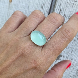 May include: A silver ring with a light blue oval gemstone.