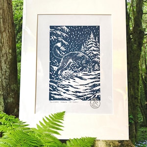 May include: A framed art print featuring a wolf in a snowy forest scene. The artwork is in shades of blue and white, with the text "Pouncing Through The Snow" at the bottom. The print is matted and framed in a white frame.
