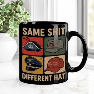 May include: Black ceramic mug featuring the text "SAME SHIT DIFFERENT HAT" and illustrations of various hats. The hats depicted are a tricorn, a Confederate cap, a military hat, and a "Make America Great Again" hat.