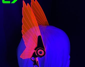 May include: A neon orange and black headpiece with wing-like structures, worn on a head with blue hair. The headpiece has a futuristic design with the text "WWW.CYBER-7.COM CYBER 7" in the upper left corner.