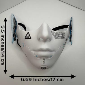 May include: White cybernetic mask with black accents, measuring 6.69 inches (17 cm) wide and 5.5 inches (14 cm) high. Features a skull and crossbones symbol, geometric designs, and blue embellishments. Includes black elastic straps.