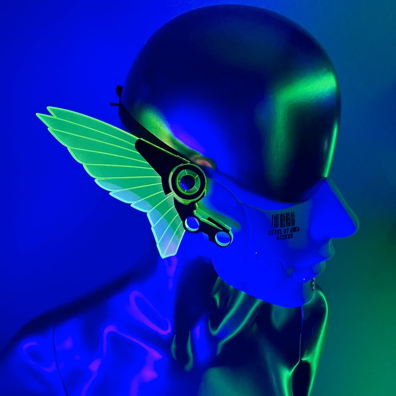 May include: A mannequin head wearing a black helmet with a green and black wing-shaped accessory attached to the side. The helmet has a barcode sticker on the side that reads "THIRD STREET 87244 12345678".
